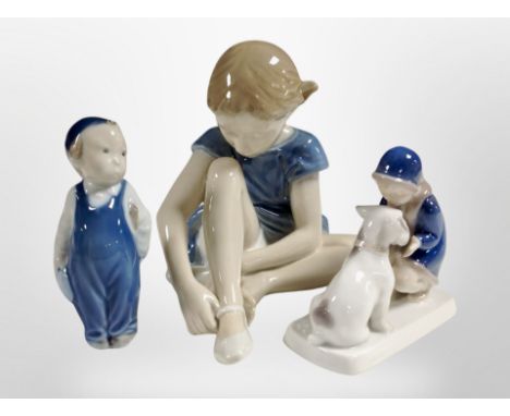 A Royal Copenhagen figure of a girl putting on ballet slippers, and two further figures, tallest 15cm.