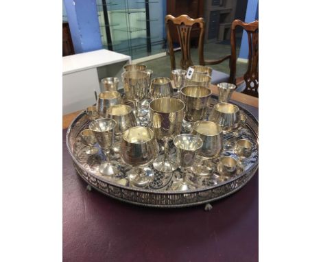 A large circular silver plated tray supported on claw feet and a selection of goblets