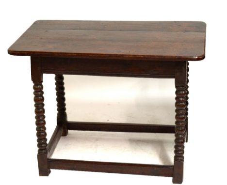 An oak centre table with plank top above ring and bobbin turned legs to block feet united by stretchers, incorporating some 1