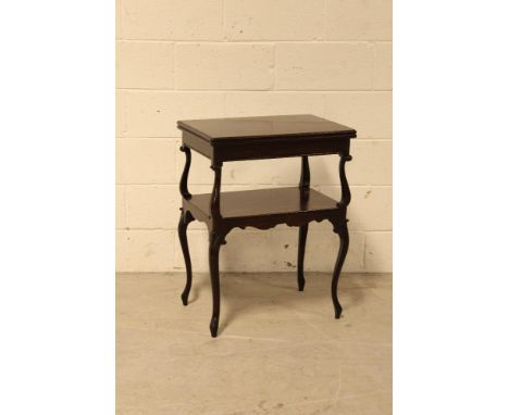 An Edwardian mahogany two tier folding card table, the twist action top on cabriole supports to single shelf over carved cabr