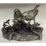 A pair of silver figures of birds on amethyst base.