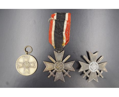 A German Third Reich War Merit Cross with swords, first class, (a/f), together with a second class award and a War Merit meda