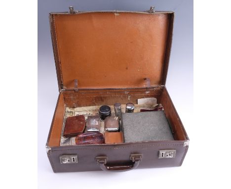 A vintage hide case containing a group of gentlemen's dressing accessories, including a razor, brushes, lidded glass jars, et