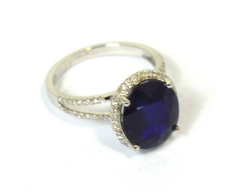 A 14k white gold and diamond ring set with an oval cut blue sapphire, approx 7.25ct, diamonds approx 0.4ct total, size M, app