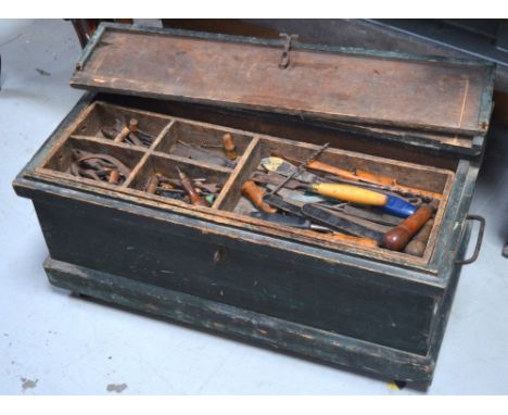 A wooden tool chest containing a quantity of tools to include saws, chisels etc.