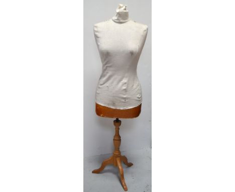 A life size dressmaker's mannequin raised on wooden tripod support.