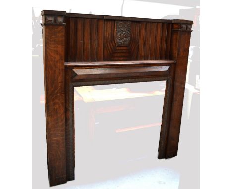 An oak and copper fire surround, oak pediment with carved floral decoration above shaped copper section with lion mask decora
