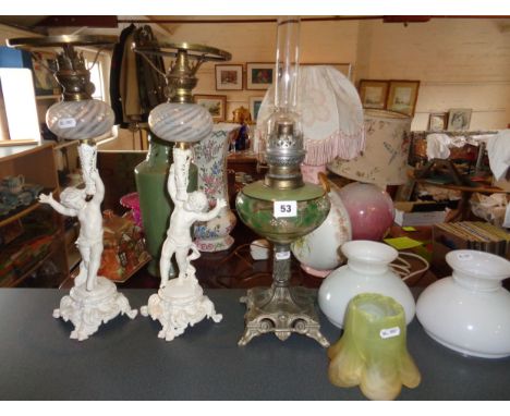 Art Nouveau oil lamp with painted glass reservoir above metal base and a pair of Victorian painted metal cherub oil lamps wit