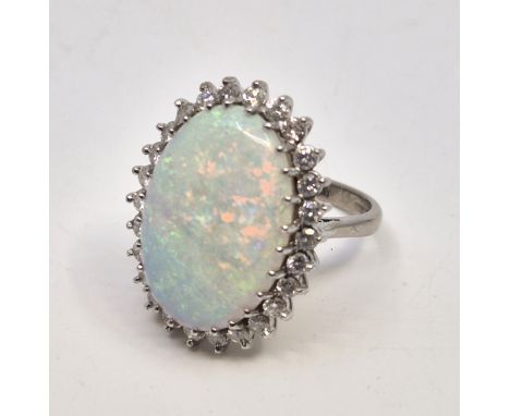 An 18ct. white gold, diamond and opal ring, set large oval cabochon opal to centre approx. 22mm x 15mm x 6.4mm bordered by ro
