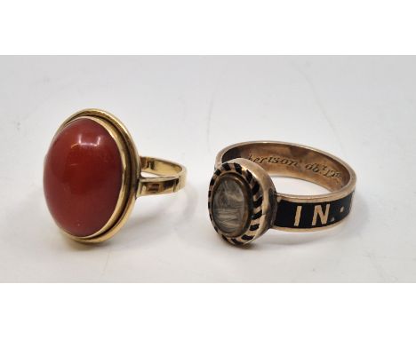 A Victorian yellow metal and black enamel mourning ring, having rub-over set oval crystal panel to front containing hair brai