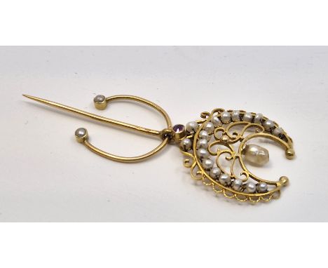 A Continental yellow metal, pearl and ruby stick pin, having upturned wire-work crescent set seventeen seed pearls with singl
