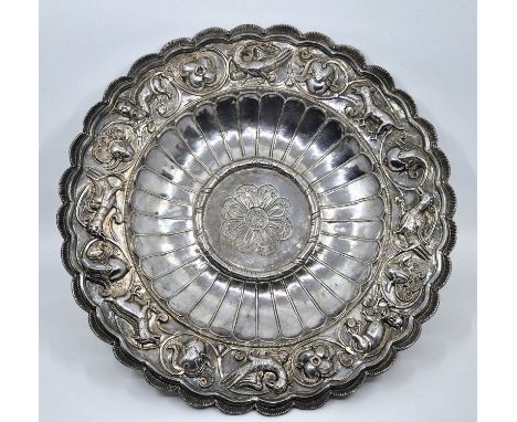 An Indian white metal lobed circular dish, having wide rim repousse and chased animals and birds within scrolling foliage (wh