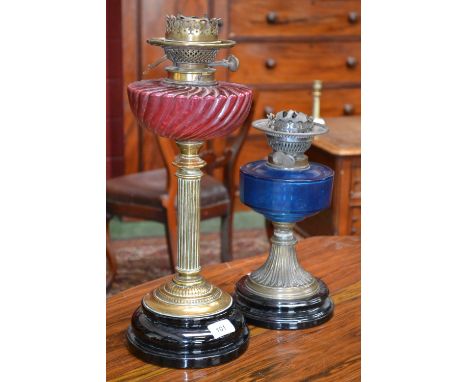 A Victorian cranberry glass and brass oil lamp; another, similar (2)