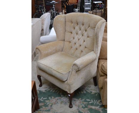An upholstered armchair, cabriole legs, button back