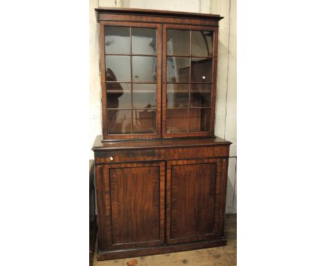 George III mahogany bookcase the moulded cornice above two glazed doors, the base with two drawers and two panelled doors on 