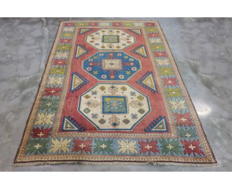 AN ANTIQUE TURKISH WOOL CARPET (315 x 222cm)
Hand knotted wool with a pale red field, three large geometric medallions, surro