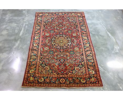 AN ANTIQUE JAMSHIDI WOOL RUG (203 x 126cm) Hand knotted wool pile with a floral medallion pattern on a red field, framed by a