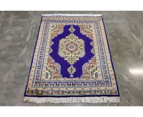 A KASHMIRI WOOL RUG (183 x 129cm)
Hand knotted wool with a deep blue field, adorned with a central floral medallion, intricat