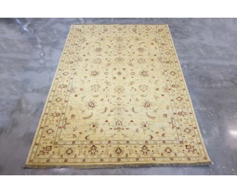 A MASHAD WOOL RUG (270 x 185cm)
Hand knotted wool with a cream field featuring sparse floral and vine motifs in soft red and 
