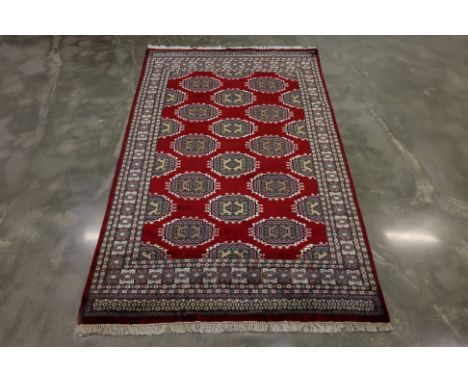 A KASHMIRI SILK AND WOOL RUG (250 x 154)
Hand knotted silk and wool with red field featuring rows of repeating octagonal guls