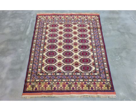A MASHAD SILK AND WOOL RUG (165 x 116cm)
Hand knotted wool with a cream field featuring rows of octagonal guls in red, blue, 