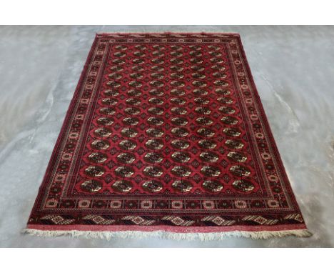 A SUPERFINE TURKMEN BOKHARA WOOL RUG (290 x 208cm) Hand knotted wool with a red field adorned with rows of 'Tekke' gul motifs