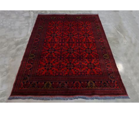 AN AFGHAN WOOL CARPET (292 x 209cm) Hand knotted wool with a red field featuring repeating octagonal guls and intricate geome