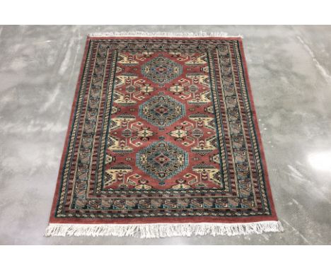 A KASHMIRI WOOL RUG (160 x 127cm)
Hand knotted wool with a red field featuring three central medallion, surrounded by geometr