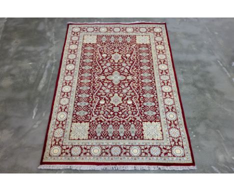 A PERSIAN MASHAD SILK AND WOOL RUG (189 x 124cm)
Hand knotted wool with a deep red field featuring intricate ivory floral and