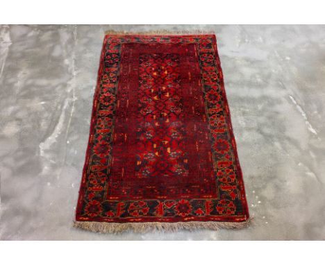 AN ANTIQUE PERSIAN WOOL RUG (193 x 110CM)
Hand knotted wool pile with a red field, geometric motifs, surrounded by a floral b