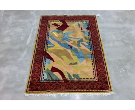 A CONTEMPORARY KASHMIRI WOOL RUG (168 x 110cm)
Hand knotted wool pile with an abstract design in earthy tones, framed by a vi
