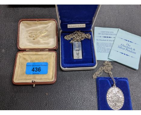 A John Pinches silver engraved pendant on chain and the Elizabeth R silver ingot pendant on chainLocation: 