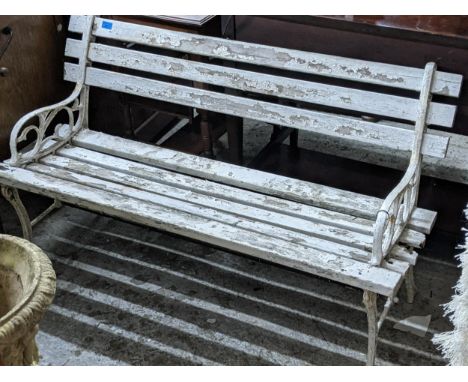 A white painted metal framed garden bench with a slatted seat and back Location: 