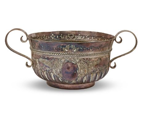 A George V silver rose bowl in the form of a William and Mary porringer, with S scroll handles and chased with a vacant carto