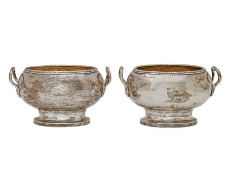 A pair of George III silver cream bowls, oval shaped with gadrooned rim, the loop handles with leaf terminals, 15.5cm over ha