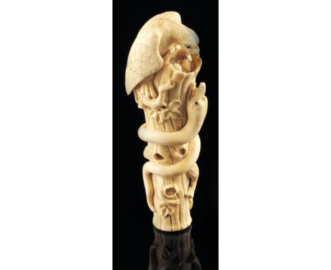 λ A Japanese carved ivory cane / parasol handle, in the form of an eagle and a snake on a tree trunk, the beasts with mother 