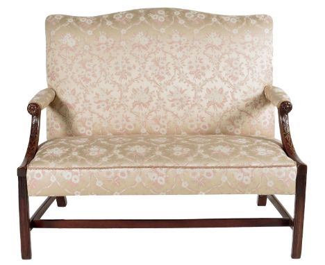 A George III mahogany two seater sofa, with a serpentine padded back above floret and husk carved arms, on moulded front legs