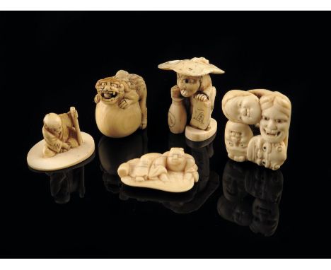 λ Five Japanese ivory carvings, comprising: four netsuke, one as a lion crouching on a rock, a recumbent man on a leaf, the b