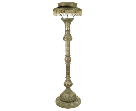 An Islamic silvered metal floor standing mosque lamp, with pierced decoration of scrolling leaves and flowers with panels of 