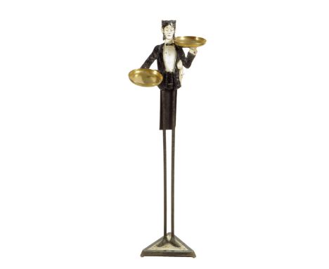 An early 20th century French cast iron card stand, in the form of a waiter carrying brass trays, with elongated legs on a tri
