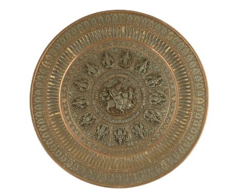 An Indian copper and silver charger, the centre with Krishna playing a flute within a border of thirteen oval rondels of poss