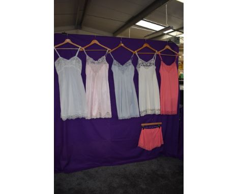 A collection of vintage nylon slips in a variety of colours, one having matching knickers.