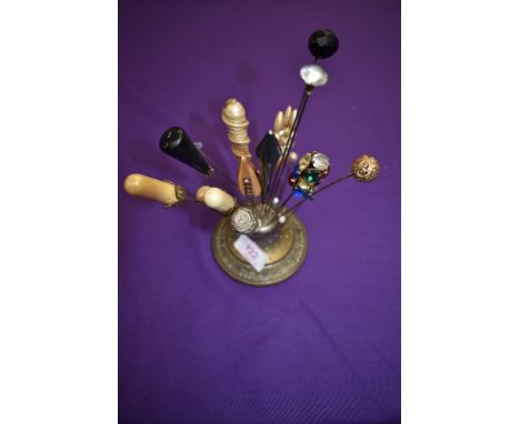 An antique hat pin holder 'Abel Morralls celebrated hat pins' and a collection of hat pins and one stick pin.