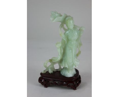 A Chinese carved jade figure of a woman holding flowers, on carved wood stand, figure 17.5cm