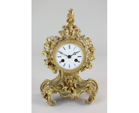 A 19th century French gilt metal cased mantel clock, the case with pineapple shaped finial and fruiting vines, on scrolled fe