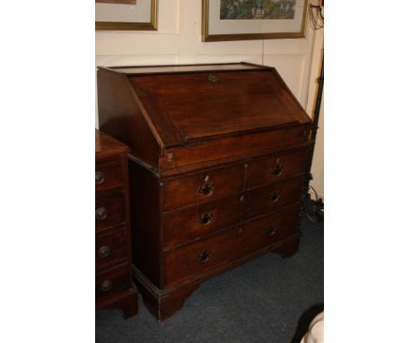 A late 18th century oak bureau in two sections, with fall front enclosing fitted interior of pigeon holes, small drawers and 