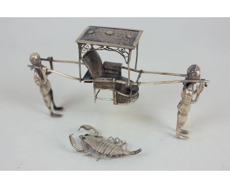 A Chinese white metal model of two men carrying a sedan chair, stamped 90, with character marks, 11cm long, together with a m