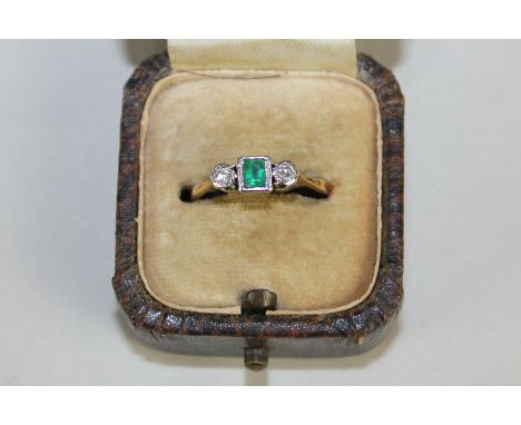 An emerald and diamond three-stone ring