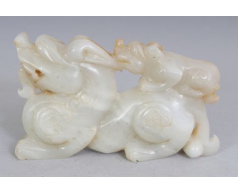 A CHINESE WHITE JADE MODEL OF A DRAGON, with its cub, the stone with ochre inclusions, 3.8in long & 2.25in high.