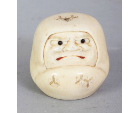 A SIGNED JAPANESE MEIJI PERIOD IVORY NETSUKE OF A DARUMA DOLL, with frowning expression, his mouth stained red, the base with